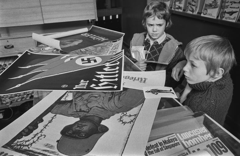 Two boys look at German propaganda from World War Two.