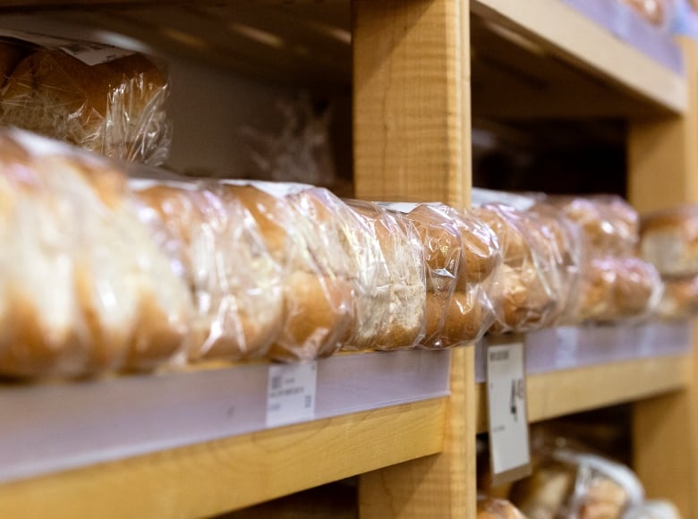 Packaged bread products sit on a grocery store shelf.