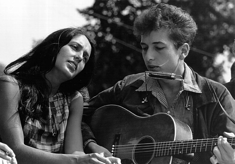Black and white photo of Joan Baez and Bob Dylan performing together in 1963.